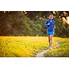 Young woman running outdoors on a lovely sunny summer evening (shallow DOF; color toned image)