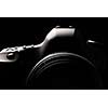 Professional modern DSLR camera low key image - Modern DSLR camera with a very wide aperture lens on
