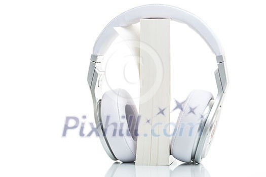 Audiobook concept - listen to your books in HD quality; hi-end hifi headphones over multiple books on white Audiobook concept - listen to your books in HD quality; hi-end hifi headphones over multiple books on white