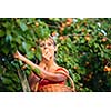 Pretty, young woman picking apricots lit by warm summer evening light (shallow DOF; color toned image)