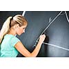 Pretty young elementary school/college teacher writing on the chalkboard/blackboa rd during a math class (color toned image; shallow DOF)