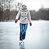 Young woman ice skating outdoors on a pond on a freezing winter day