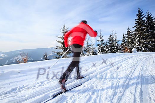 Cross-country skiing: young man cross-country skiing on a lovely sunny winter day (motion blur technique is used to convey movement)