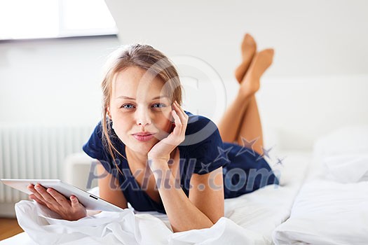 Pretty, young woman using her tablet computer in bed, after coming home from work (shallow DOF; color toned image) Pretty, young woman using her tablet computer in bed, after coming home from work (shallow DOF; color toned image)