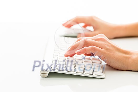 Hands of a person working an a keyboard over white background (color toned image; shallow DOF) Hands of a person working an a keyboard over white background (color toned image; shallow DOF)
