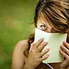 Cute young woman  covering her face with a book she is reading