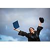 Pretty, young woman celebrating joyfully her graduation - spreading wide her arms, holding her diploma, savouring her success (color toned image; shallow DOF)