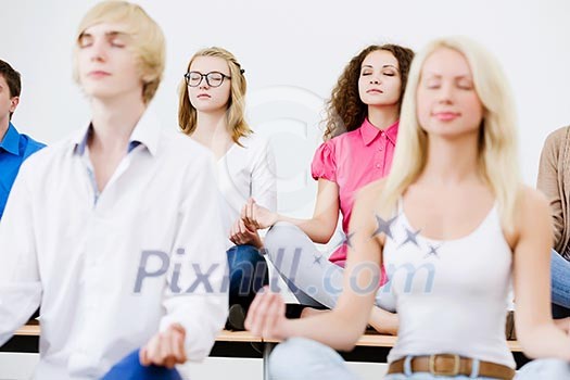 group of young people meditating on table in classroom group of young people meditating on table in classroom