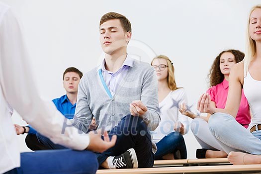 group of young people meditating on table in classroom group of young people meditating on table in classroom