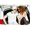 Young happy couple sitting in car trunk outdoor