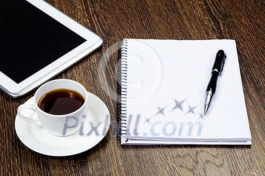 Tablet pc cup of coffee and notepad at table Tablet pc cup of coffee and notepad at table