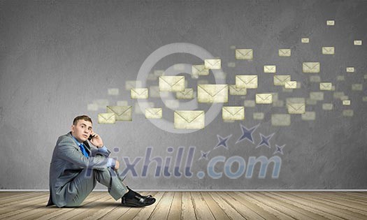Image of young man sitting on floor and using mobile phone Image of young man sitting on floor and using mobile phone