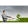 Young businessman cutting bush in shape of dollar
