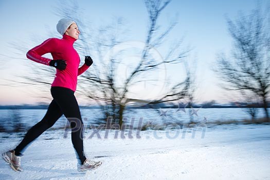 Young woman running outdoors on a cold winter day (motion blurred image) Young woman running outdoors on a cold winter day (motion blurred image)