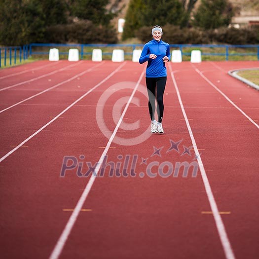 Young woman running at a track and field stadium Young woman running at a track and field stadium