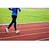 Young woman running at a track and field stadium (motion blurred image)