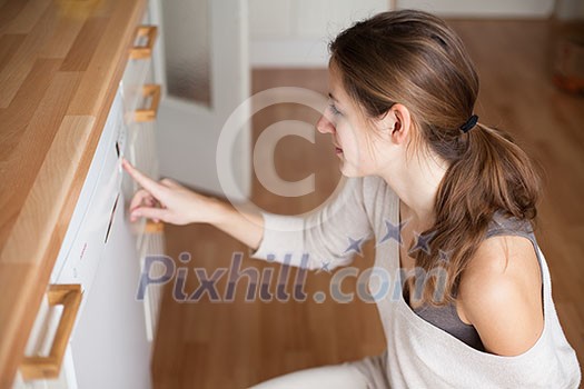 Housework: young woman putting dishes in the dishwasher Housework: young woman putting dishes in the dishwasher