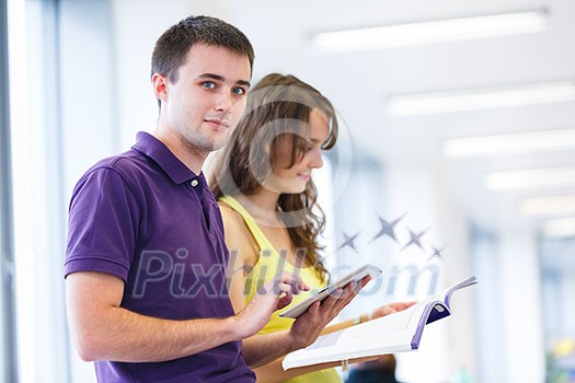 Two college students in library, reading books, using tablet computer (color toned image; shallow DOF) Two college students in library, reading books, using tablet computer (color toned image; shallow DOF)