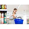 Beautiful young woman shopping in a grocery store/supermarket (color toned image)