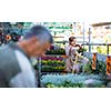 Young woman buying flowers at a garden center (color toned image; shallow DOF)