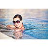 Portrait of a young woman relaxing in a swimming pool (shallow DOF; color toned image)