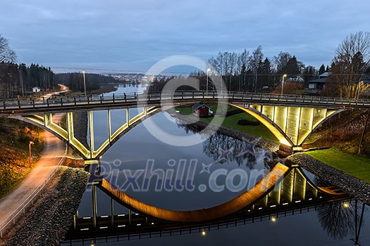 Bridge over calm river in evening lights Bridge over calm river in evening lights