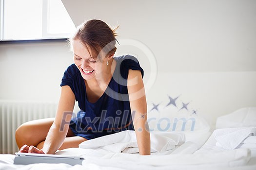 Elegant, smart, young woman using her tablet computer in bed (shallow DOF; color toned image) Elegant, smart, young woman using her tablet computer in bed (shallow DOF; color toned image)