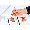 Close up of male hand holding pen and pointing at graphs