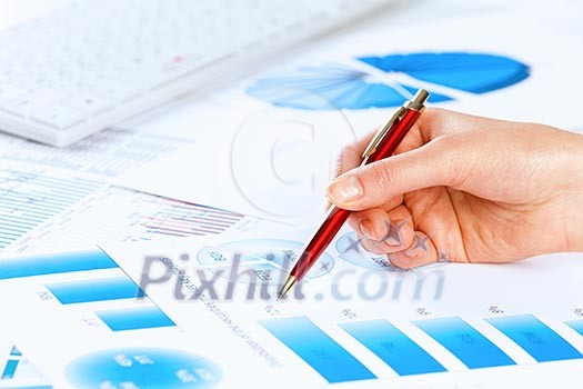 Close up of male hand holding pen and pointing at graphs Close up of male hand holding pen and pointing at graphs