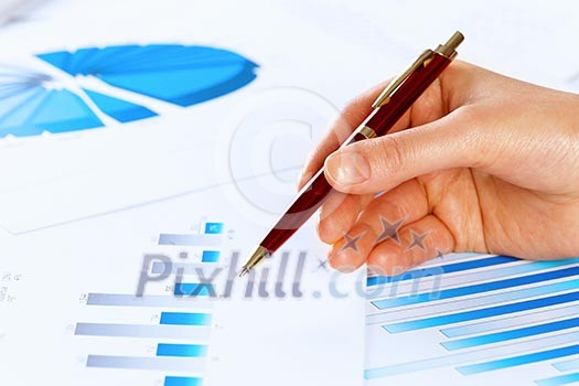 Close up of male hand holding pen and pointing at graphs Close up of male hand holding pen and pointing at graphs