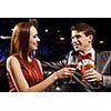 Young handsome man in restaurant accompanied by elegant lady