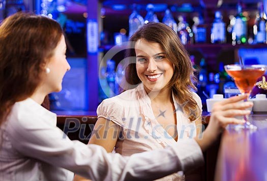Two young pretty women a bar drinking cocktails Two young pretty women a bar drinking cocktails