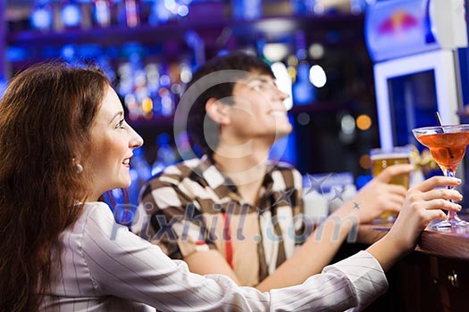 Young couple in bar having drinks and talking Young couple in bar having drinks and talking