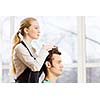 Young man in chair at barbers and woman hairdresser