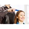 Young woman in chair at barbers and male hairdresser