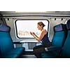 Young woman traveling by train, using her smartphone while sitting on board, alone