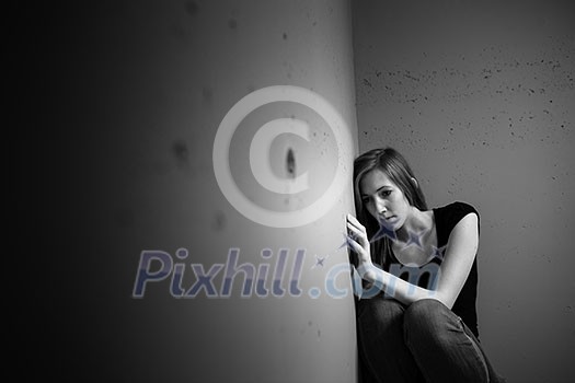 Young woman suffering from a severe depression (very harsh lighting is used on this shot to underline/convey the gloomy mood of the scene) Young woman suffering from a severe depression (very harsh lighting is used on this shot to underline/convey the gloomy mood of the scene)