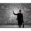 Rear view of businesswoman looking at business sketches on wall
