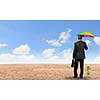 Rear view of businessman with umbrella protecting sprout