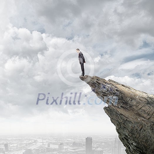 Young businessman standing on edge of rock mountain Young businessman standing on edge of rock mountain