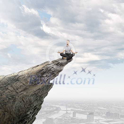 Young businesswoman sitting lotus pose on edge of rock mountain Young businesswoman sitting lotus pose on edge of rock mountain