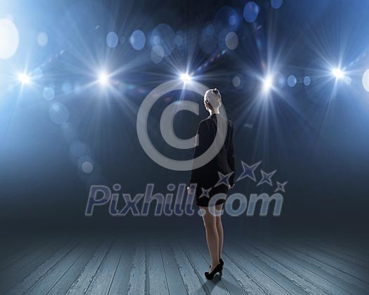Rear view of businesswoman standing in lights of stage Rear view of businesswoman standing in lights of stage