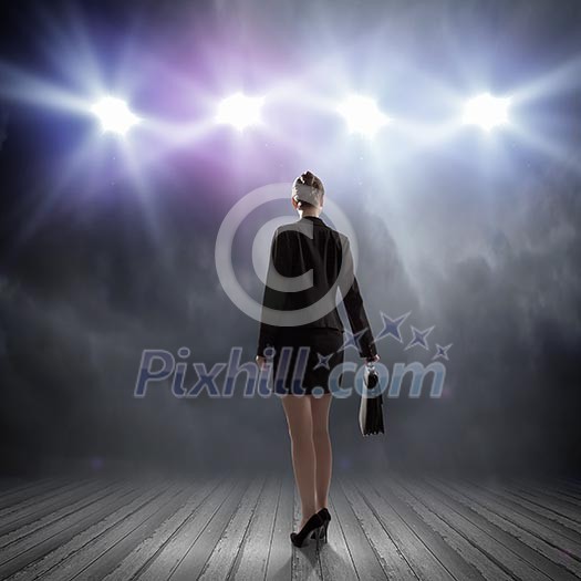 Rear view of businesswoman standing in lights of stage Rear view of businesswoman standing in lights of stage