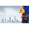 Close up of woman mechanic with yellow helmet in hand against city background