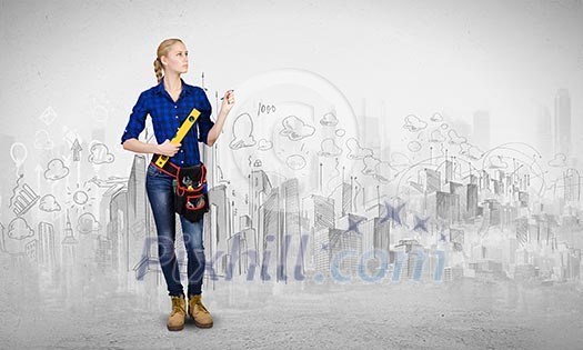 Young woman mechanic with ruler in hand against city background Young woman mechanic with ruler in hand against city background