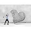 Aggressive businessman breaking stone heart with hammer