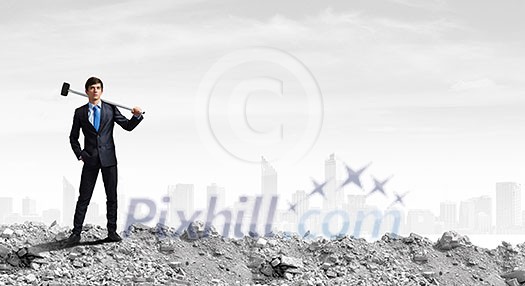Young determined businessman with hammer in hands Young determined businessman with hammer in hands