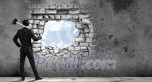 Young determined businessman with hammer in hands Young determined businessman with hammer in hands