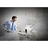 Young angry businessman crashing bricks with hammer