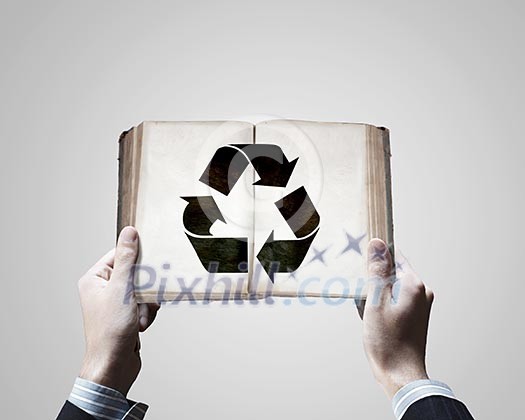 Close up f male hands holding opened book with recycle sign Close up f male hands holding opened book with recycle sign